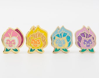 May include: Four enamel pins featuring a cartoon cat face with a flower design. The pins are in pink, yellow, blue, and purple.