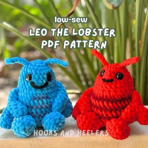 May include: Two crocheted lobster plushies, one blue and one red, with black eyes and smiling mouths. The plushies are sitting on a light brown surface. The text "low-sew LEO THE LOBSTER PDF PATTERN" is above the plushies. The text "HOOKS AND HEELERS" is below the plushies.