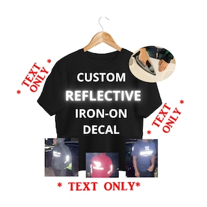 Pode incluir: Uma camiseta preta num cabide de madeira com o texto branco CUSTOM REFLECTIVE IRON-ON DECAL. A imagem inclui um detalhe mostrando um ferro de passar aplicando o decalque e três fotos pequenas com o material refletivo em várias roupas.