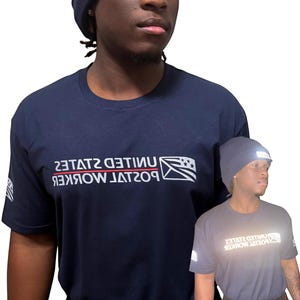 Könnte beinhalten: Ein marineblaues Kurzarm-T-Shirt mit weißem reflektierendem Text, der UNITED STATES POSTAL WORKER lautet, sowie einer Flaggengrafik. Das Design ist auf der Brust und auf dem Ärmel gedruckt. Das T-Shirt wird mit einer passenden Mütze kombiniert.