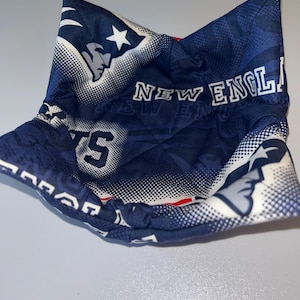 May include: A blue and white fabric bowl with a New England Patriots logo and the words "New England Patriots" printed on it.
