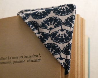 May include: A triangular fabric corner bookmark featuring a dark navy blue and off-white floral fan pattern. The bookmark is placed over the top corner of a book page that contains the printed text: Galileo! La terra sta benissimo, sostenitori, possiamo affermare.