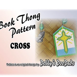May include: A beaded cross bookmark pattern with the text "Book Thong Pattern CROSS". The bookmark features a cross design in yellow, green, and white, with blue accents. A silver charm of praying hands and a green bead are attached.
