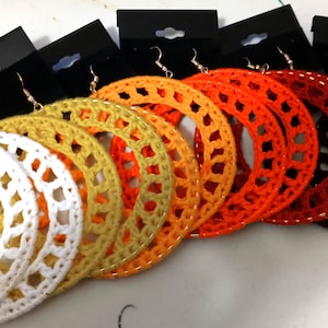 May include: Set of six pairs of large crocheted hoop earrings in white, yellow, orange, red, and brown.
