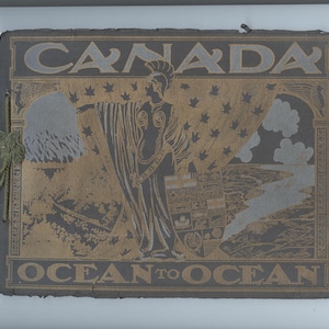 Puede incluir: Grabado antiguo con la palabra "CANADA" en la parte superior y "OCEAN TO OCEAN" en la parte inferior. La imagen presenta a una mujer con un vestido fluido, señalando un paisaje con montañas y agua. El grabado tiene una combinación de colores dorados y grises.