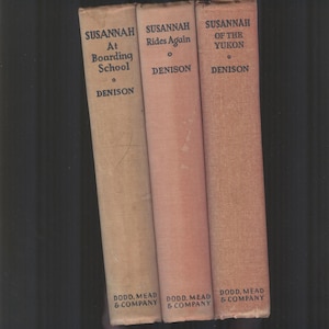 Könnte beinhalten: Drei Vintage-Taschenbücher mit dem Titel "Susannah" auf den Rückseiten. Die Bücher sind betitelt mit "Susannah At Boarding School", "Susannah Rides Again" und "Susannah Of The Yukon". Alle drei Bücher wurden von Dodd, Mead & Company veröffentlicht.