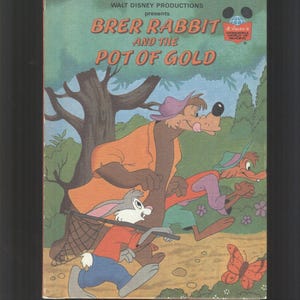 Può includere: Una copertina di un libro per bambini vintage con illustrazioni di Brer Rabbit, un orso e una volpe. Il titolo è "Brer Rabbit and the Pot of Gold" e il libro è presentato da Walt Disney Productions.