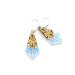 May include: A pair of geometric earrings with a wood and iridescent blue design. The earrings are shaped like a diamond and have a silver hook.