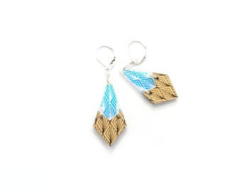 May include: A pair of geometric wood earrings with a blue and white geometric pattern. The earrings are made of wood and have a silver hook.