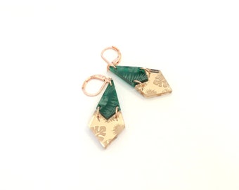 May include: A pair of gold and green geometric earrings with a floral pattern. The earrings are made of acrylic and have a rose gold finish.