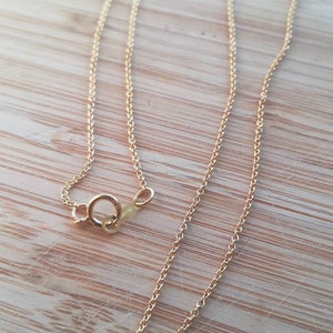 K&ouml;nnte beinhalten: Eine goldene Kettenkette mit einem Karabinerverschluss. Die Kette besteht aus kleinen, runden Gliedern.