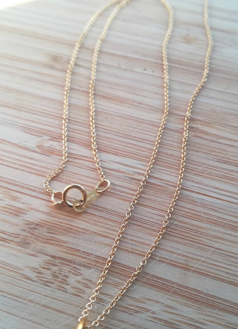 K&ouml;nnte beinhalten: Eine goldene Kettenkette mit einem Karabinerverschluss. Die Kette besteht aus kleinen, runden Gliedern.
