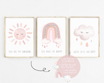 May include: Three watercolor prints with pink and orange color schemes. The first print features a pink sun with a smiling face and the text "You are my sunshine". The second print features a pink rainbow with clouds and the text "You make me happy". The third print features a pink cloud with a smiling face and the text "When skies are grey".