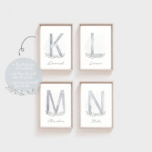 Puede incluir: Cuatro impresiones enmarcadas con ilustraciones de acuarela de las letras K, L, M y N. Cada letra est&aacute; rodeada de un c&iacute;rculo con un dise&ntilde;o floral y un nombre debajo: Konrad, Lenni, Marlon y Nils.