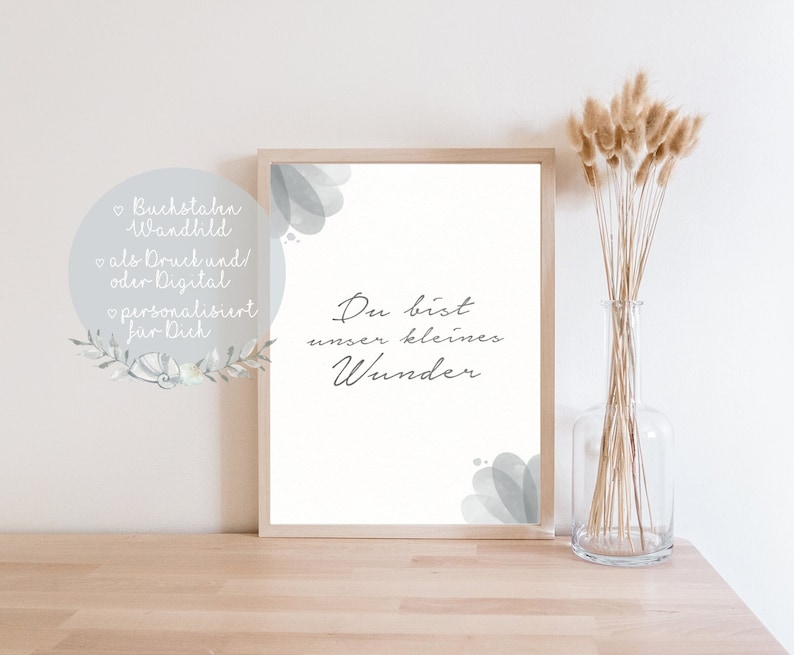 Puede incluir: Una impresi&oacute;n enmarcada con fondo blanco y dise&ntilde;os grises que parecen acuarela. El texto "Du bist unser kleines Wunder" est&aacute; escrito en letra cursiva negra.