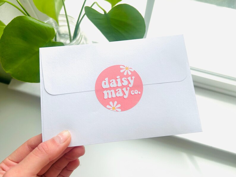 May include: White envelope with a pink circle sticker that says "daisy may co." in white text with white daisy illustrations.