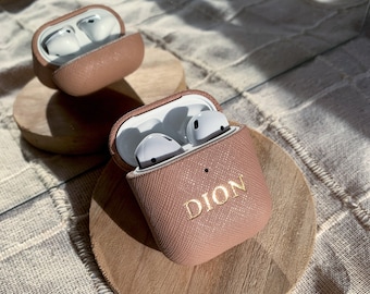 May include: A pink leather Airpods case with the name "DION" embossed in gold lettering.