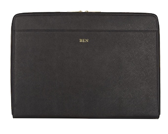 Può includere: Custodia per laptop in pelle nera con cerniera dorata e la parola "BEN" impressa in oro sul davanti.