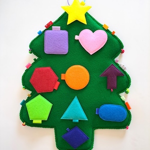 May include: A felt Christmas tree with a yellow star on top and various colored felt shapes attached to it, including a square, heart, hexagon, circle, arrow, pentagon, triangle, and oval.