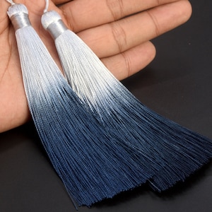 Può includere: Due frange a degradè con un gradiente dal bianco al blu scuro. Le frange sono realizzate con fili morbidi e setosi e sono perfette per aggiungere un tocco di eleganza a qualsiasi progetto.