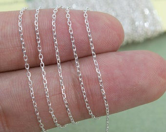 May include: Close-up of silver chain links. The chain is delicate and has a smooth, polished finish.
