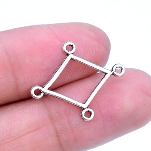 May include: Silver-toned metal connector with a diamond shape and four jump rings. The connector is designed for jewelry making.