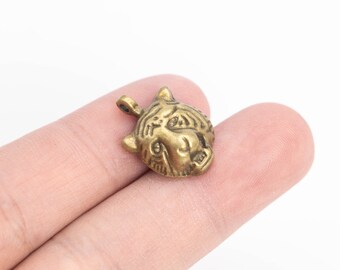 May include: A gold-toned metal pendant featuring a detailed tiger head design. The pendant has a loop at the top for attaching to a chain or cord.