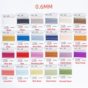 May include: A variety of silk thread spools in various colors, including white, black, gray, and gold. Each spool is labeled with the text "100% Silk" and "0.6MM". Each spool comes with a needle and 2 meters of thread.