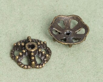 Può includere: Due decorazioni decorative in metallo color oro antico con disegni intricati. Uno ha una forma circolare con un foro centrale e un bordo rialzato e testurizzato. L'altro ha una forma a fiore con un foro centrale e un design traforato.