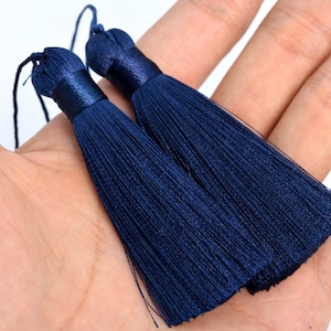 Puede incluir: Dos borlas azul marino con una parte superior envuelta en satén y una cuerda en bucle para colgar. Las borlas están hechas de muchos hilos de seda. Estas borlas decorativas se utilizan a menudo para la fabricación de joyas.