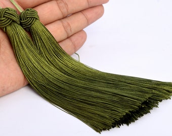 May include: Two green silk tassels with knotted tops. The tassels are long and flowing, and they are perfect for adding a touch of elegance to any project.