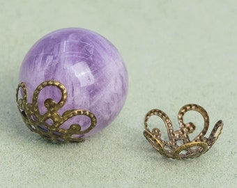May include: A purple amethyst gemstone ball with a decorative metal cap. The cap is ornate and has a floral design.