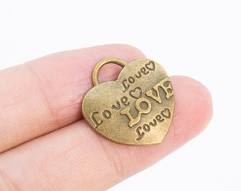 May include: A gold-toned heart-shaped charm with the word "LOVE" inscribed in the centre and the phrase "Love forever" around the edge.