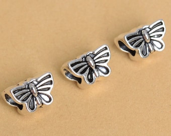 May include: Three silver butterfly-shaped bead caps. Each cap has a detailed butterfly design with black wings and a silver body.