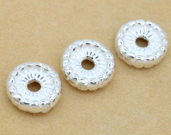 May include: Three silver-toned metal spacer beads with a decorative, raised, floral design. The beads are round in shape with a hole in the centre.