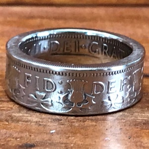 May include: A silver ring made from a repurposed coin. The ring features the inscription "FID. DEF." and a thistle design. The inscription "DEI. GRAT." is visible on the inside of the ring.