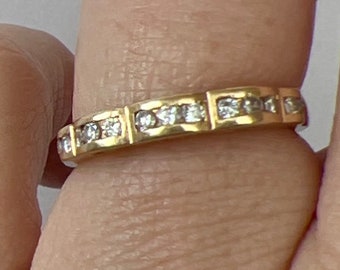 May include: A gold band ring with a row of small, clear diamonds set in a square shape.