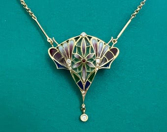 May include: A gold necklace with a pendant featuring a colorful enamel design with a floral motif and diamond accents. The pendant is shaped like a teardrop and hangs from a delicate chain.
