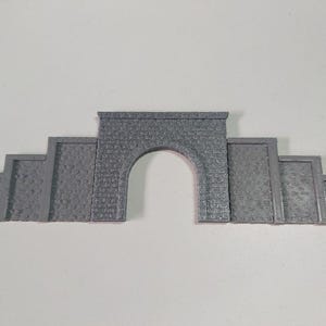 May include: A grey stone model train tunnel entrance with a rounded archway. The tunnel entrance is made of multiple pieces that can be assembled to create a realistic tunnel effect.