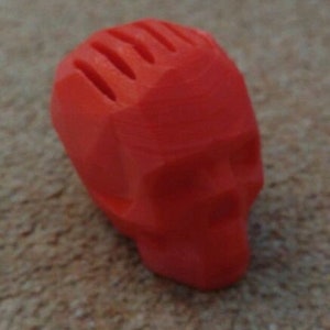 May include: A bright red, 3D printed skull with a geometric design. The skull has a textured surface and is missing the top of the head.