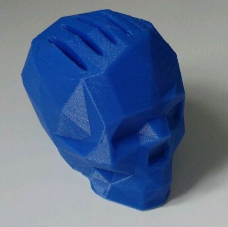 May include: A blue 3D printed skull with a geometric design. The skull is made of plastic and has a smooth finish.