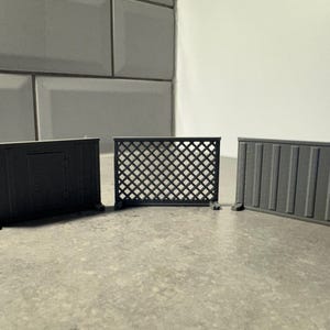 May include: Three miniature grey fences. One is a solid panel, another has a lattice design, and the third has vertical slats. Each fence has small feet for stability, suitable for a miniature garden or model display.
