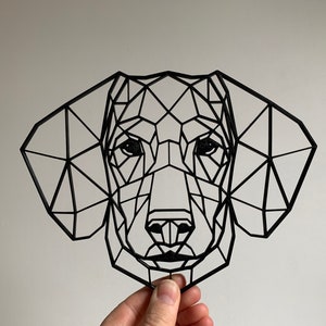May include: Black geometric dachshund dog wall art. The dog's head is constructed from interconnected black lines, creating a modern, polygonal design. The artwork features a detailed depiction of the dog's face, including eyes, nose, and ears.