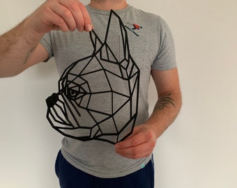 May include: Black geometric wall art in the shape of a dog's head. The artwork is made of connected lines, creating a low-poly design. The dog's eye and snout are clearly defined. The art is held up by a person.