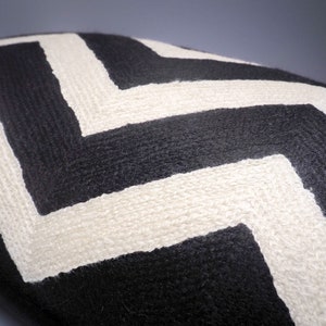 May include: Black and white chevron patterned throw pillow. The pillow is made of a soft, textured fabric.