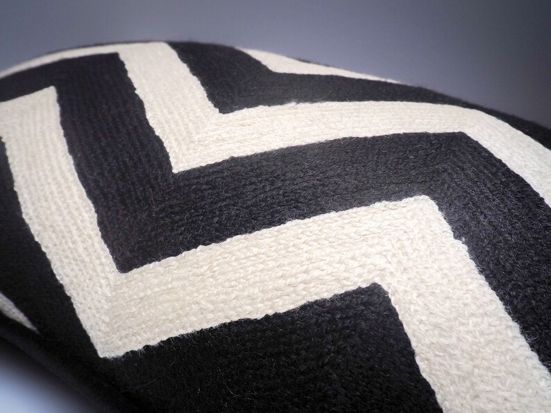 May include: Black and white chevron patterned throw pillow. The pillow is made of a soft, textured fabric.