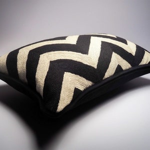 May include: Black and white chevron patterned throw pillow with a black border.