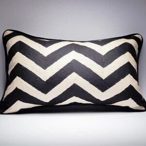 May include: Black and white chevron patterned throw pillow with a black border.