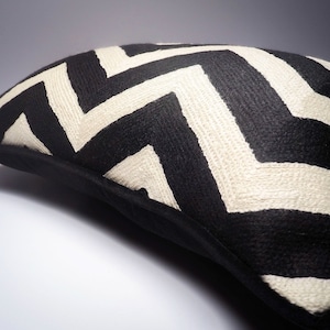 May include: Black and white chevron patterned throw pillow with a black border.