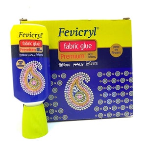 May include: A blue and yellow tube of Fevicryl fabric glue with a paisley design on the front. The tube is labeled "fabric glue Premium" and "Fast Drying". The text "ज़्यादा चिपकाए" is also visible on the box.